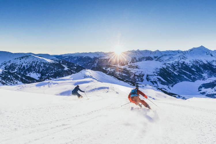2 skiers carving down Gerlosski slope at sunet