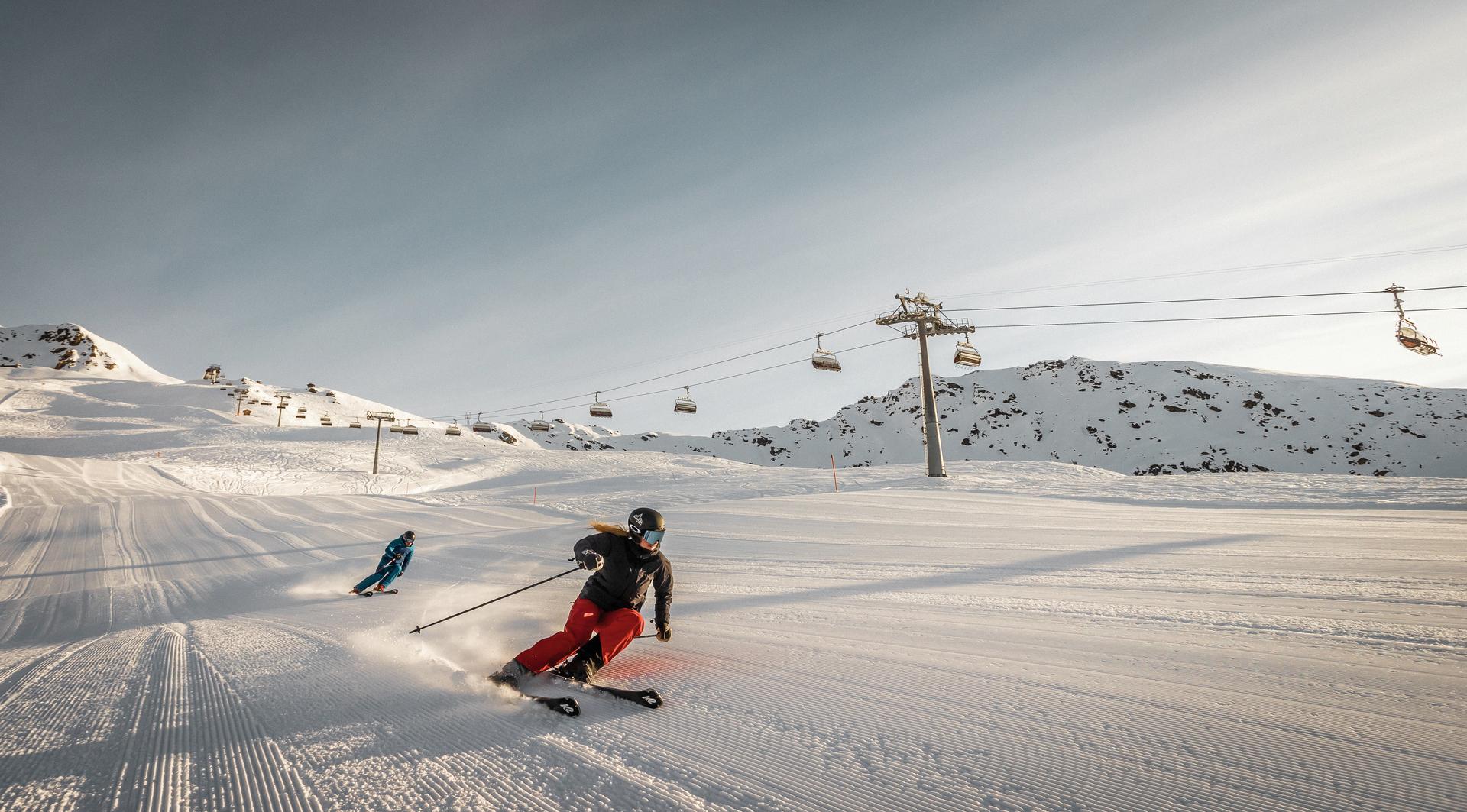 2 Skiiers skiin down slope at sunset at Davos ski resort